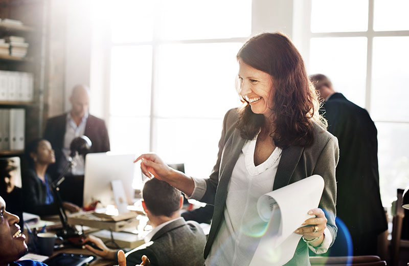 Woman smiling in a corporate office talking to man